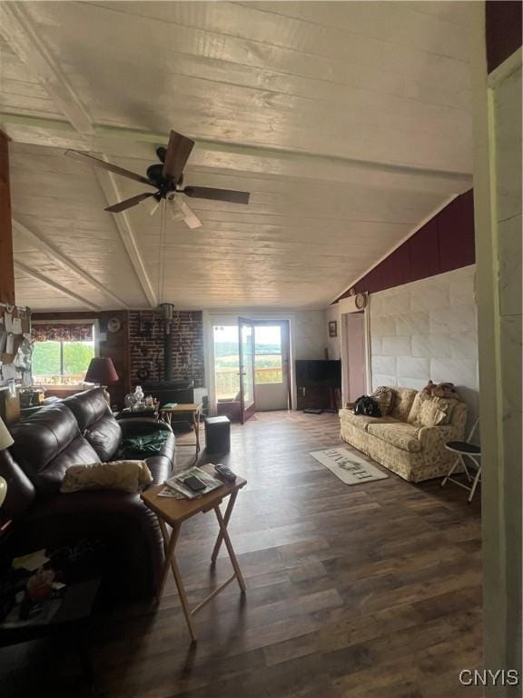 living room featuring vaulted ceiling with beams, plenty of natural light, hardwood / wood-style flooring, and a wood stove