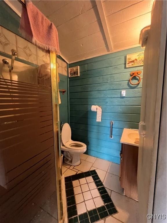 bathroom with wood walls, tile patterned flooring, vanity, walk in shower, and toilet