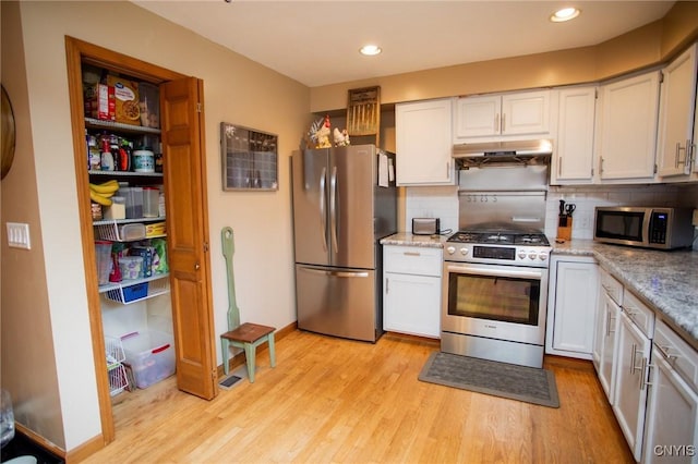 kitchen with light hardwood / wood-style flooring, white cabinetry, backsplash, stainless steel appliances, and light stone counters