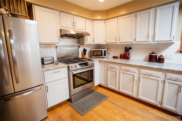 kitchen featuring stainless steel appliances, white cabinetry, light stone counters, and light hardwood / wood-style flooring