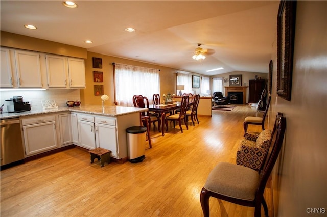 kitchen featuring ceiling fan, stainless steel dishwasher, kitchen peninsula, and white cabinets