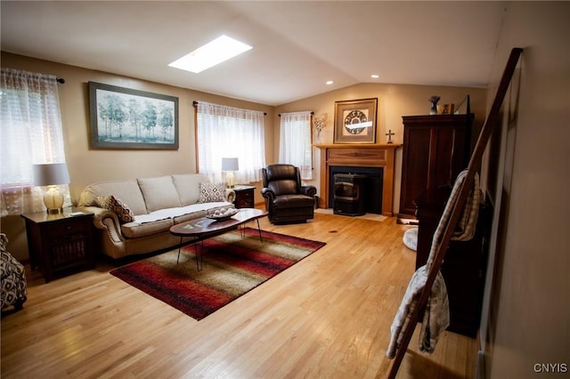 living room with light hardwood / wood-style floors and vaulted ceiling with skylight