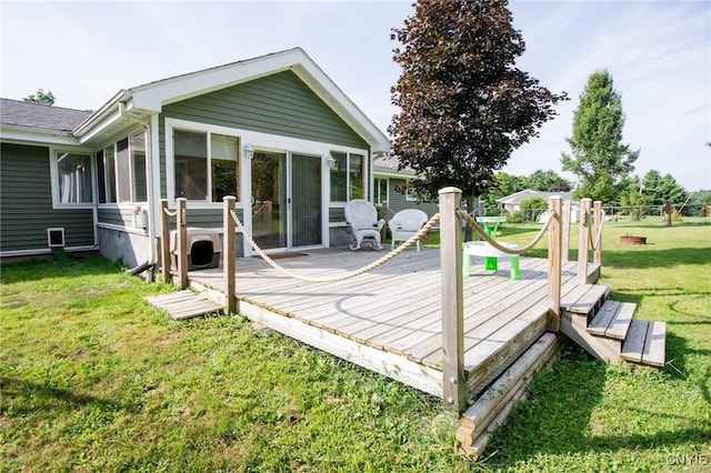 rear view of house with a wooden deck, a yard, and a sunroom