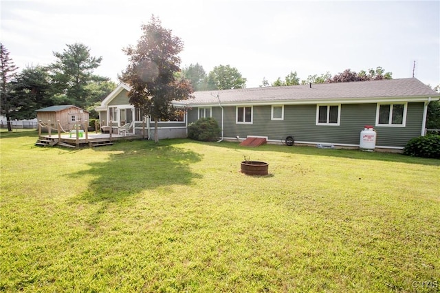 rear view of house with a fire pit, a lawn, and a deck