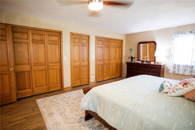 bedroom featuring ceiling fan, multiple closets, and light wood-type flooring