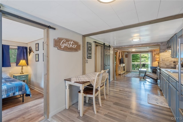 dining area with light wood-type flooring and a barn door