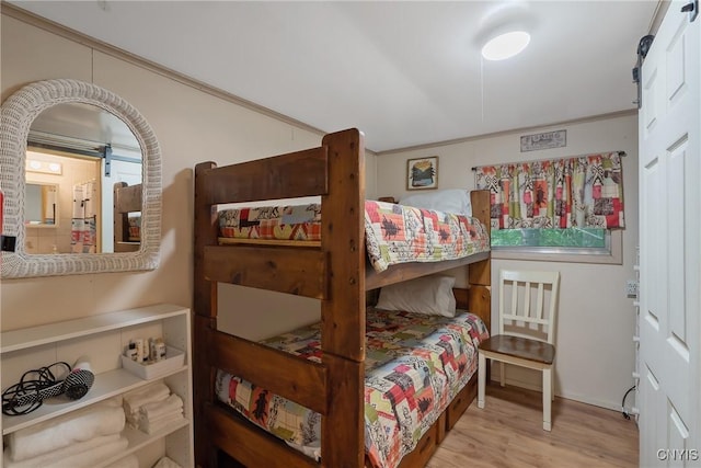 bedroom with ornamental molding and wood finished floors