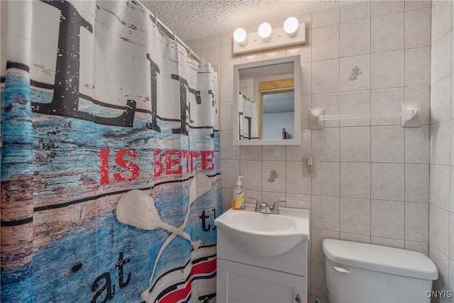 bathroom with backsplash, a textured ceiling, vanity, tile walls, and toilet