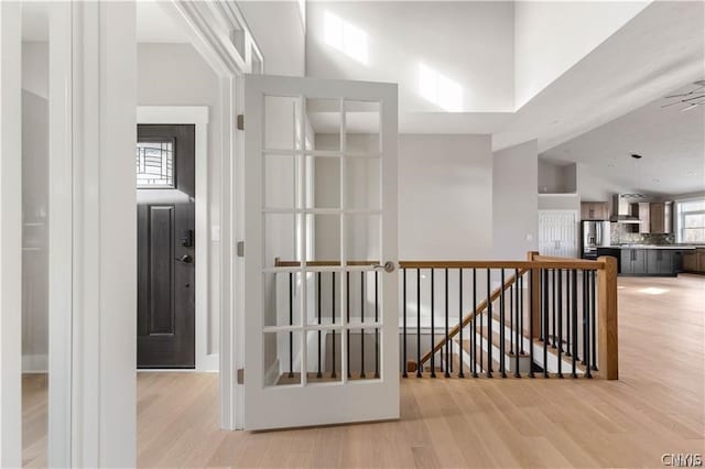 hallway with light hardwood / wood-style flooring and a high ceiling