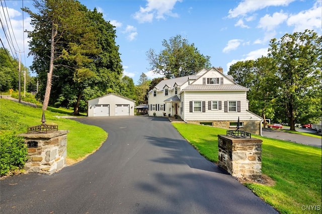 view of front of house featuring a garage, a front lawn, and an outbuilding