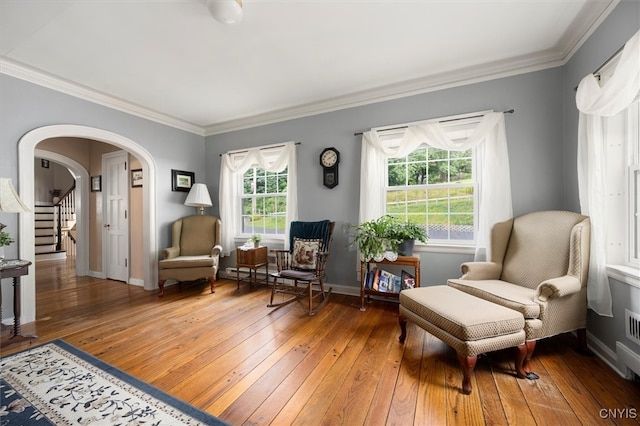 living area with wood-type flooring, crown molding, and a healthy amount of sunlight