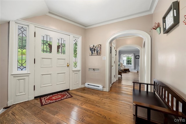 entrance foyer with ornamental molding, baseboard heating, and hardwood / wood-style floors