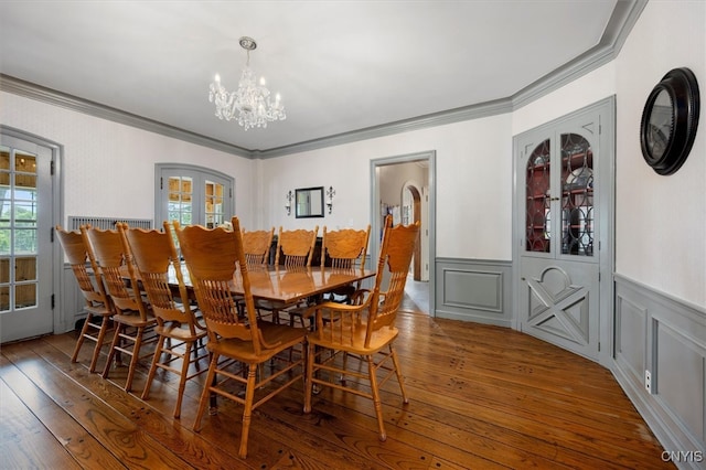 dining space featuring hardwood / wood-style flooring, a notable chandelier, and crown molding