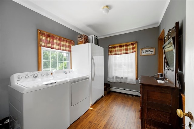 laundry area featuring washer and clothes dryer, a baseboard heating unit, and hardwood / wood-style floors