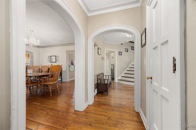 corridor featuring an inviting chandelier, crown molding, and wood-type flooring