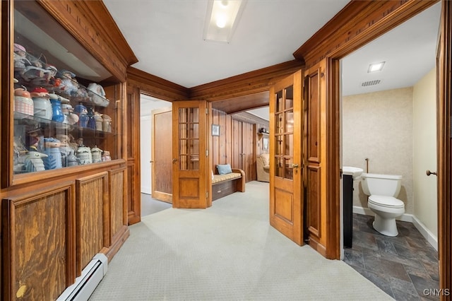 hallway with wood walls, baseboard heating, and carpet