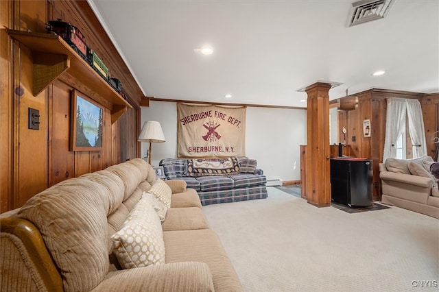 living room featuring carpet flooring, crown molding, wooden walls, decorative columns, and a baseboard radiator