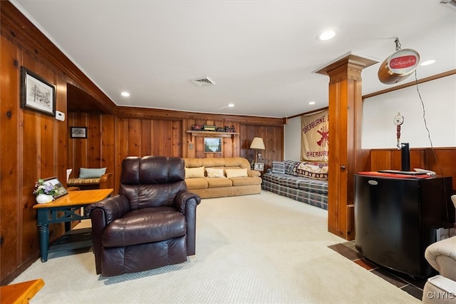 living area with decorative columns, wooden walls, carpet floors, and ornamental molding