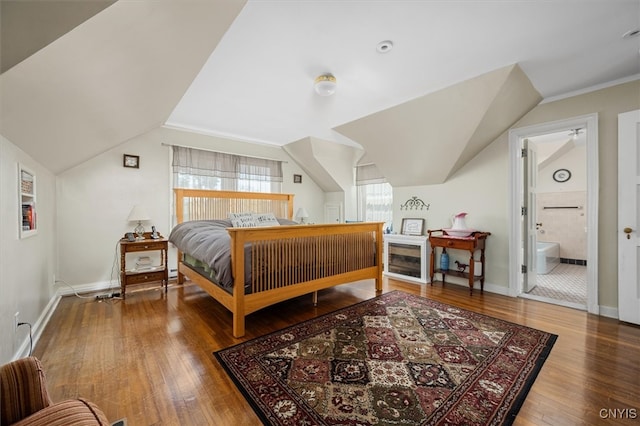 bedroom featuring hardwood / wood-style flooring, connected bathroom, and lofted ceiling