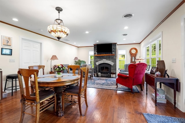 dining area featuring brick wall, a fireplace, crown molding, and dark hardwood / wood-style floors