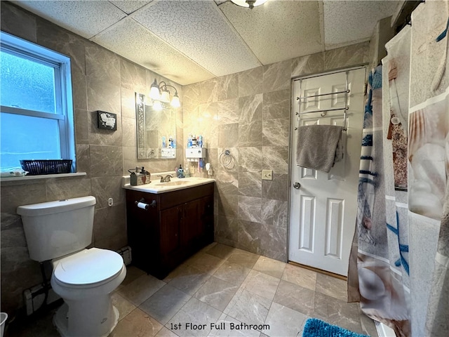 bathroom with vanity, tile patterned flooring, a paneled ceiling, tile walls, and toilet