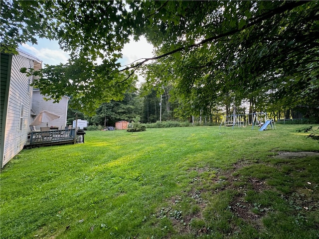 view of yard with a deck, a playground, and a shed