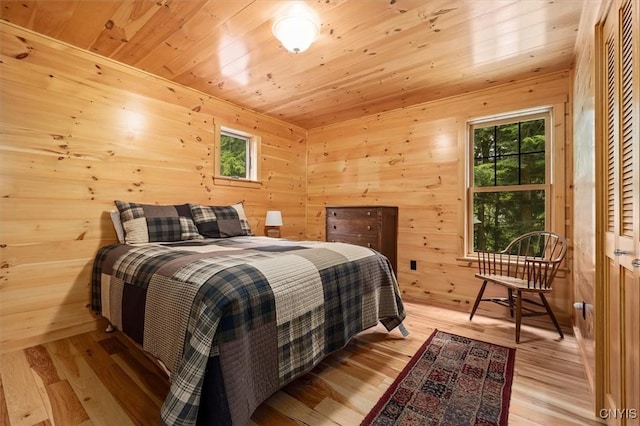 bedroom with wooden walls, wooden ceiling, and light hardwood / wood-style flooring