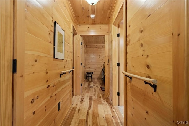 hall with hardwood / wood-style floors, wooden ceiling, and wood walls