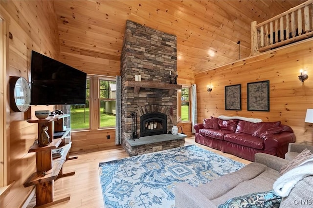 living room featuring wooden walls, light hardwood / wood-style flooring, high vaulted ceiling, wood ceiling, and a stone fireplace