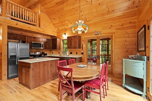 kitchen featuring stainless steel appliances, a center island, french doors, high vaulted ceiling, and decorative light fixtures