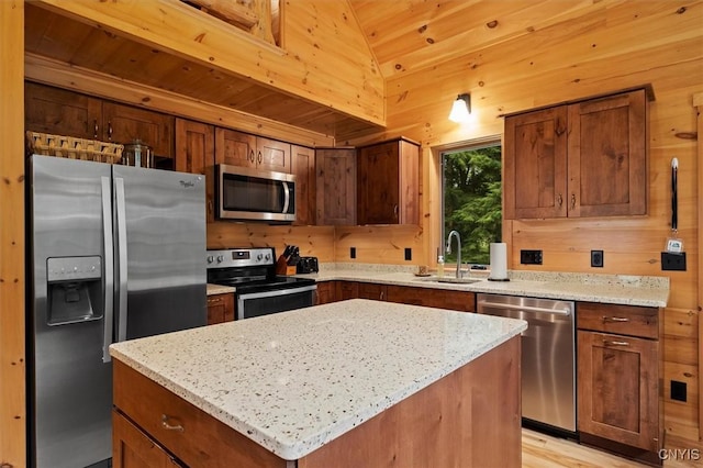 kitchen with a kitchen island, stainless steel appliances, light stone countertops, and sink