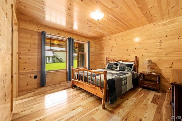 bedroom featuring wooden walls, wood ceiling, and light hardwood / wood-style flooring