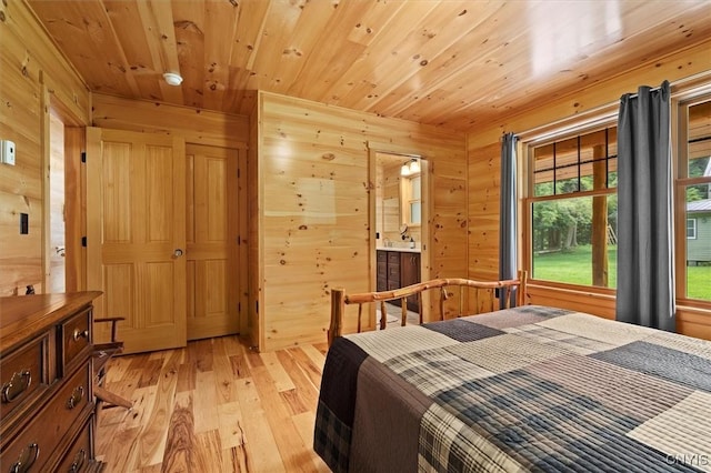 bedroom featuring wooden ceiling, wood walls, connected bathroom, and light hardwood / wood-style floors