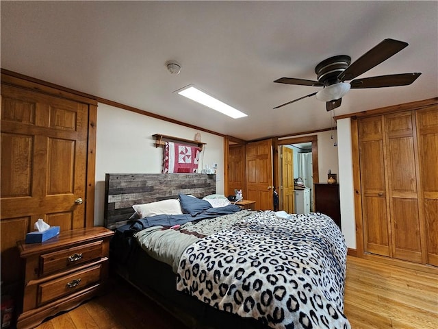 bedroom featuring ornamental molding, light wood-style flooring, and a ceiling fan