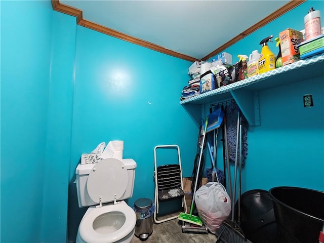bathroom with toilet, crown molding, and wood finished floors