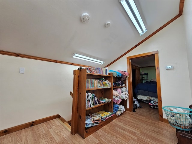 interior space featuring ornamental molding, light wood-type flooring, and vaulted ceiling