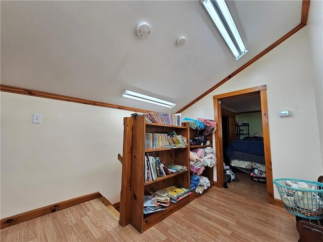 hall with baseboards, lofted ceiling, wood finished floors, and crown molding