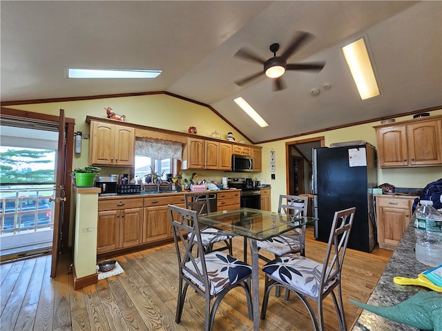 dining space with vaulted ceiling, sink, light wood-type flooring, and ceiling fan