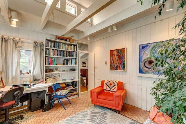 living area featuring wooden walls, built in desk, and beam ceiling