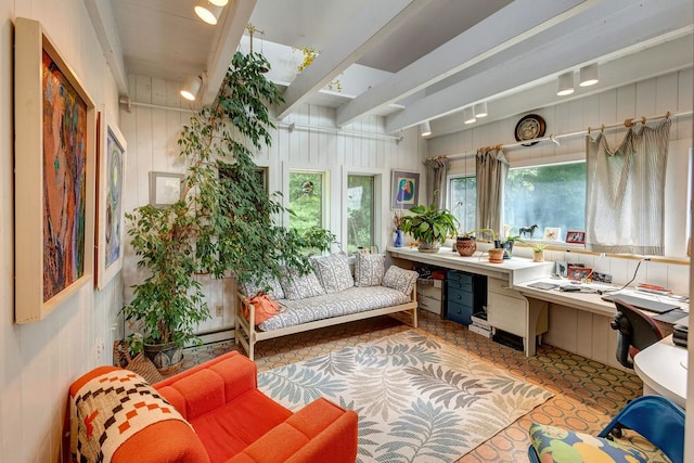 interior space featuring beamed ceiling, track lighting, a wealth of natural light, and built in desk