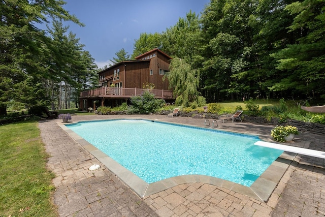 view of pool with a yard, a deck, a diving board, and a patio area