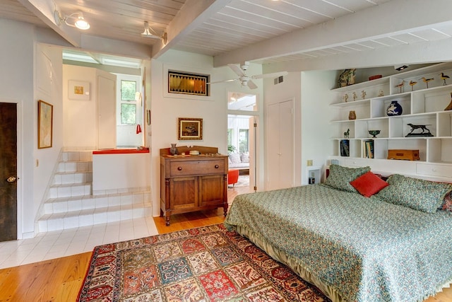 bedroom featuring wood-type flooring, vaulted ceiling with beams, and ceiling fan