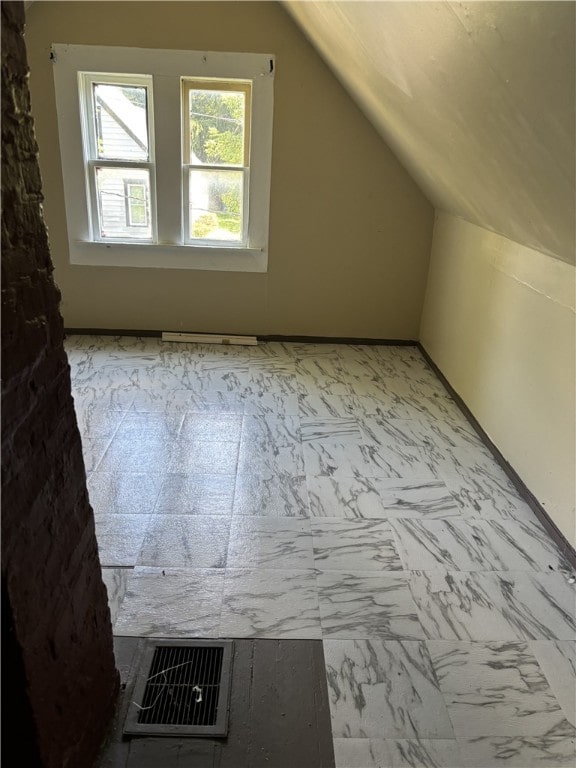 bonus room with lofted ceiling and light tile patterned floors