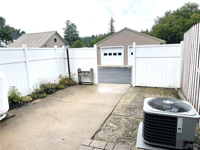 detached garage with central air condition unit, driveway, and fence