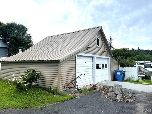 detached garage featuring driveway and fence