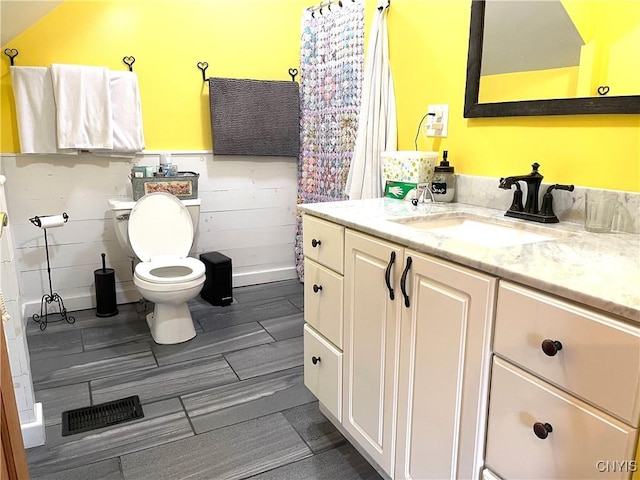 bathroom with vanity, wood finished floors, visible vents, wainscoting, and toilet