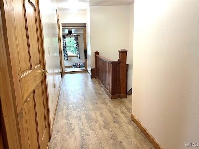 hallway featuring an upstairs landing, light wood-type flooring, and baseboards