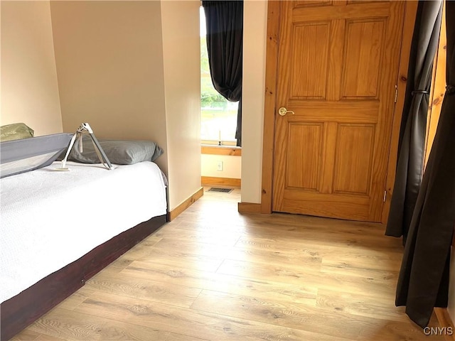 bedroom with baseboards, visible vents, and light wood finished floors