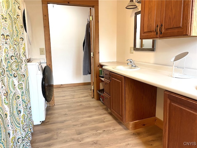 kitchen with sink, washing machine and dryer, and light hardwood / wood-style flooring