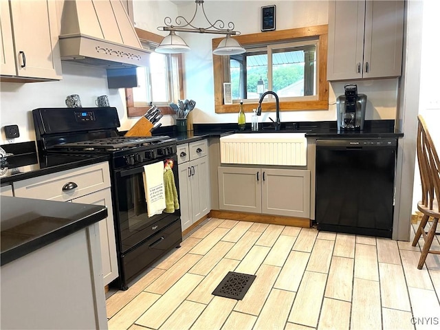 kitchen featuring wood finish floors, custom exhaust hood, a sink, black appliances, and dark countertops